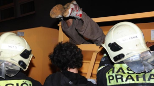 ilustrační foto z novinky.cz, kde vidíme 2 hasiče z Prahy, kteří pomáhají muži, kterému čouhají z kontejneru nohy ven.